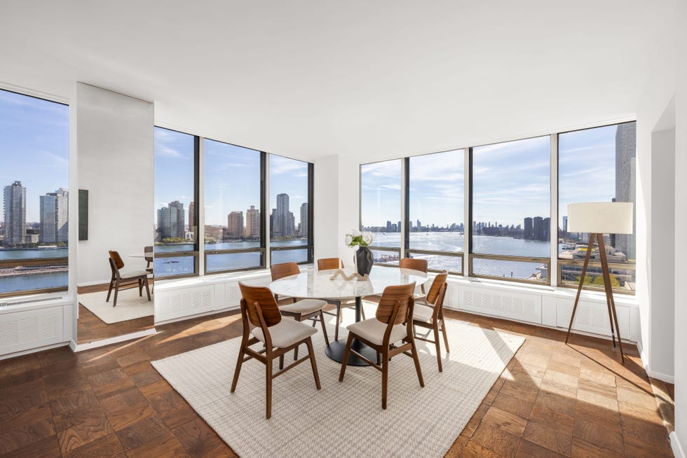 Bright dining area with a round table and river view through large windows. Bright dining area with a round table and river view through large windows.
