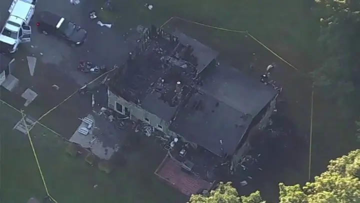 Aerial view of a house in Greenville, NY, damaged by a blaze with emergency vehicles nearby.