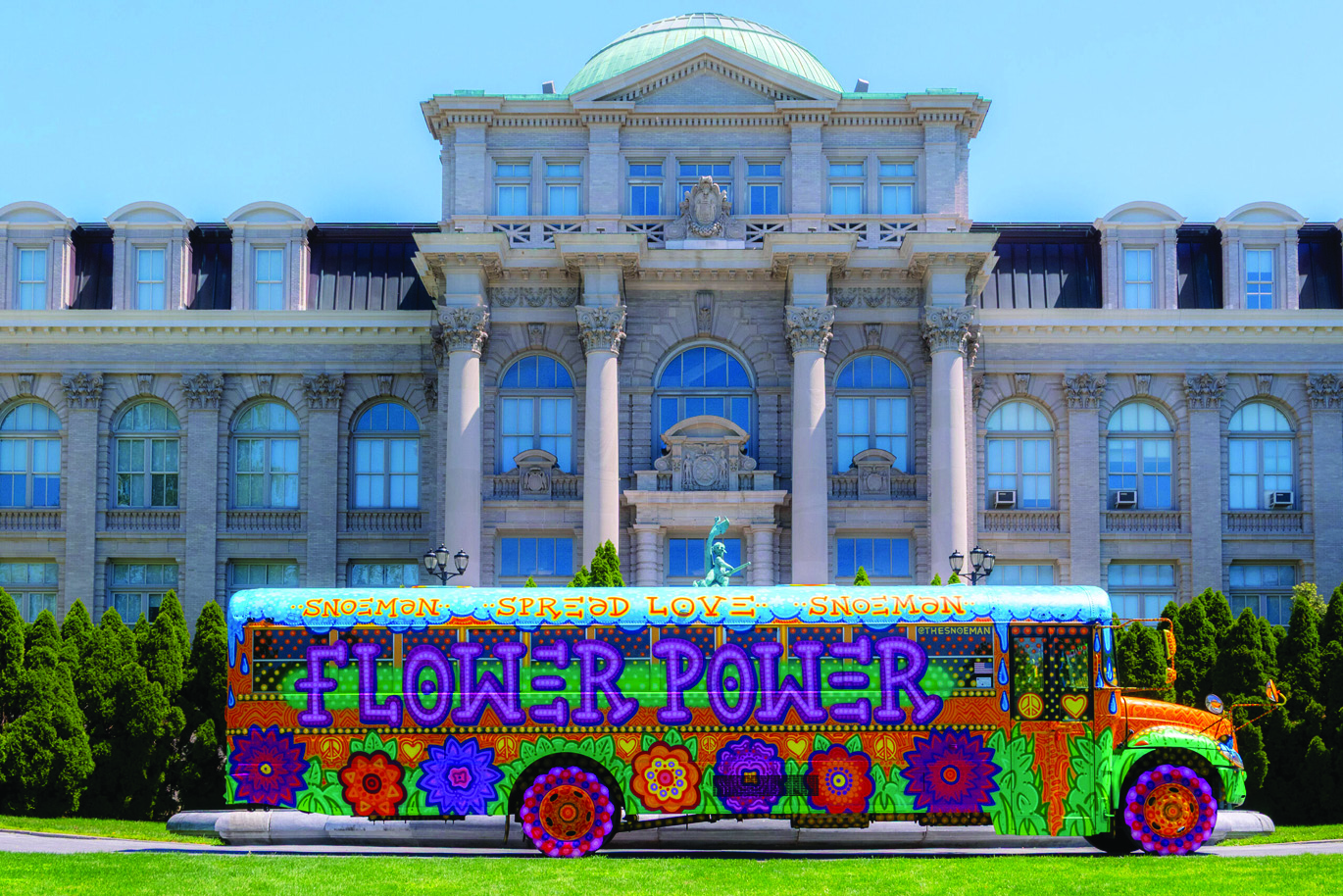 Colorful psychedelic bus with flower patterns in front of a grand stone building.