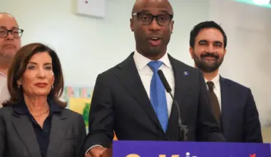 Kamar Samuels, NYC education chancellor, standing next to Mayor Mamdani and Governor Hochul.