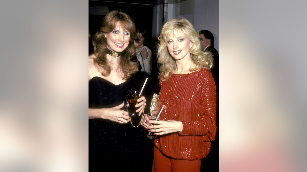 Morgan Fairchild wearing all red with her sister wearing all black in the 1980s.
