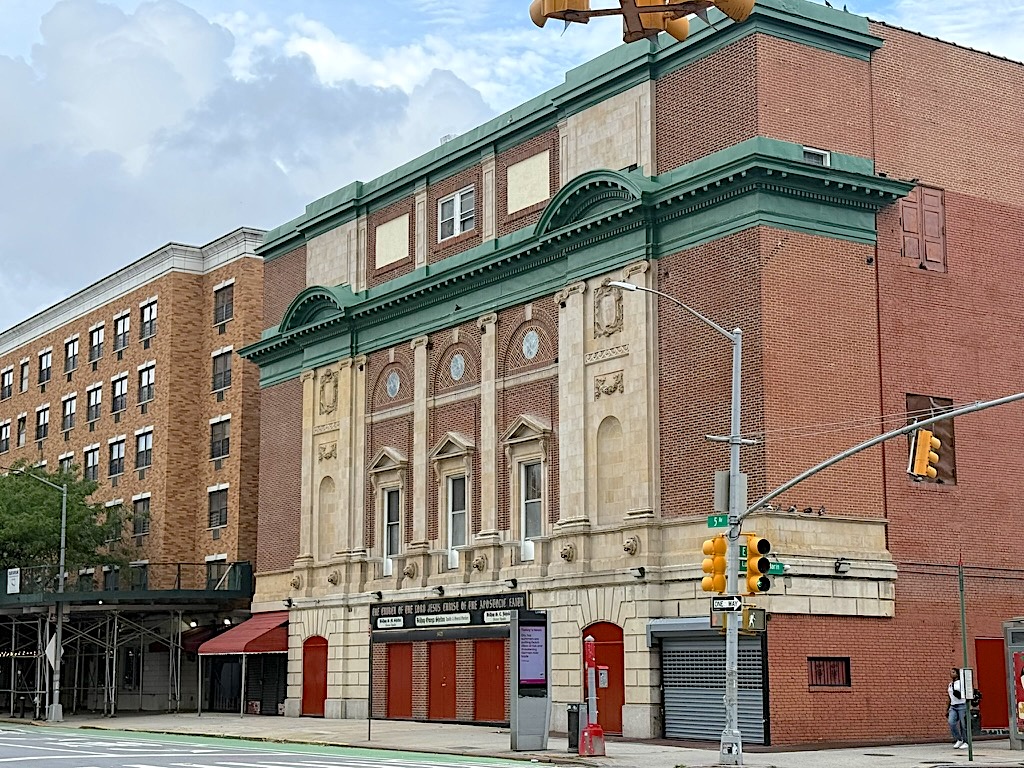 Historic theater building with ornate architecture, featuring a green roof and decorative façade, located on a street corner.