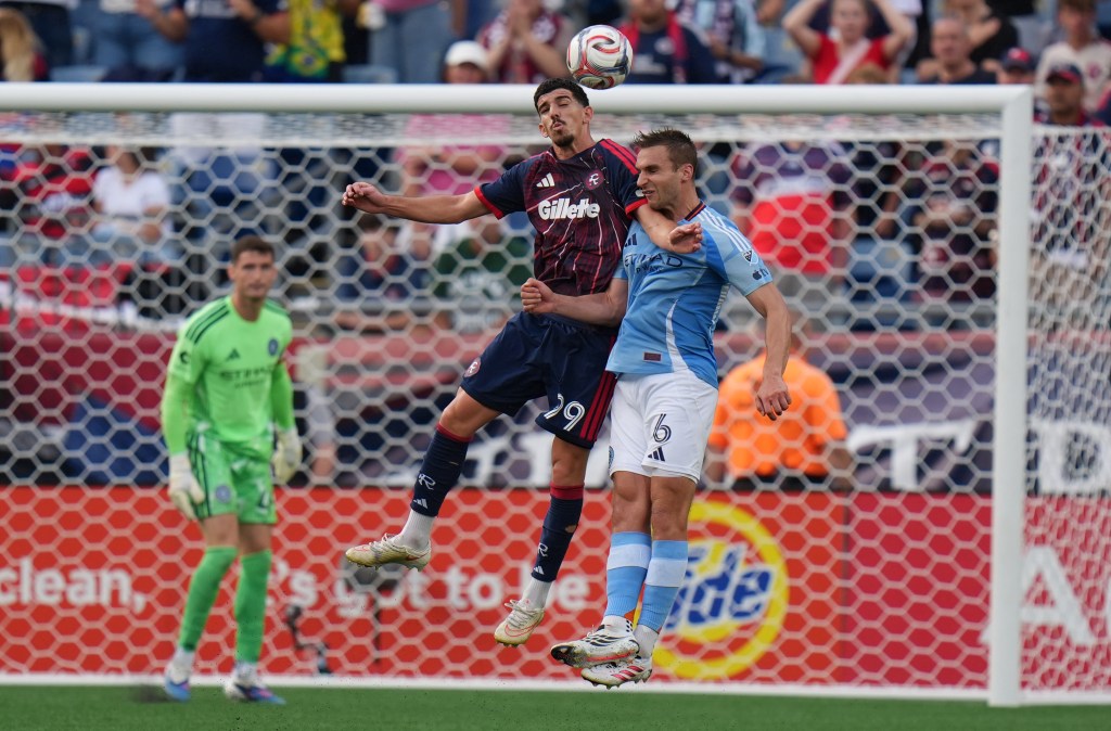 New England Revolution's Dor Turgeman and New York City FC's James Sands leap for a header in front of the goal.