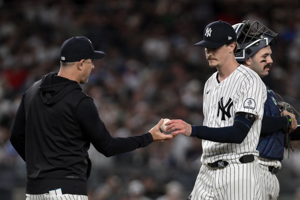 New York Yankees pitcher Max Fried (54) hands the ball to manager Aaron Boone during a baseball game.
