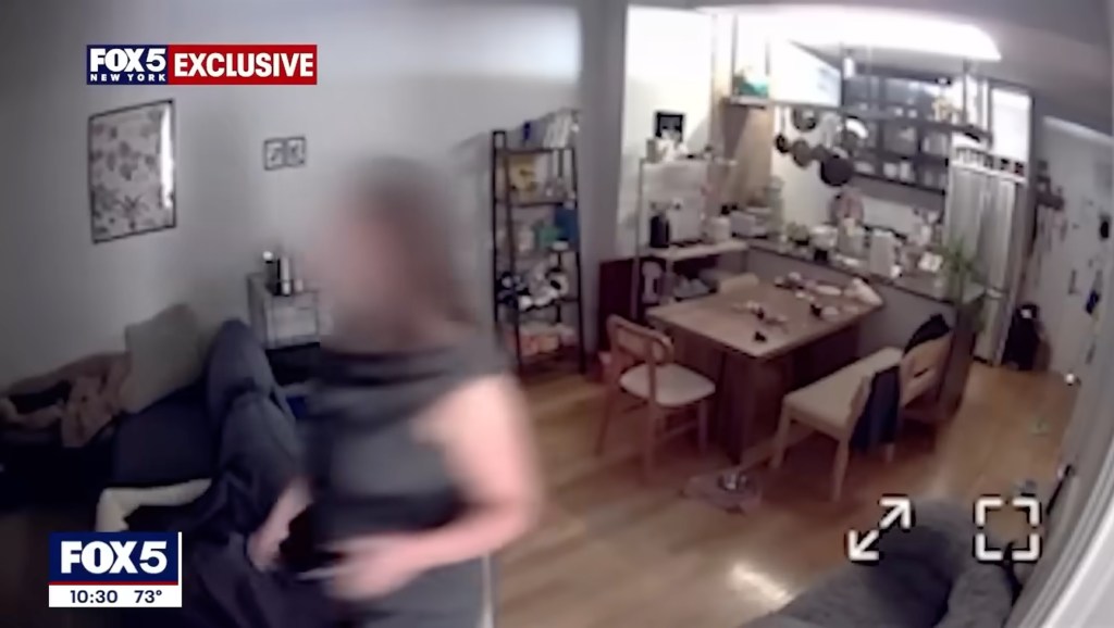 A blurred woman walks through an apartment living room and kitchen.