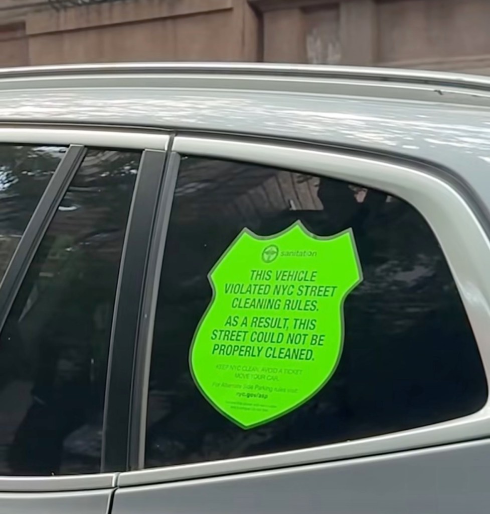 A neon-green shield-shaped sticker on a car window reads "THIS VEHICLE VIOLATED NYC STREET CLEANING RULES."