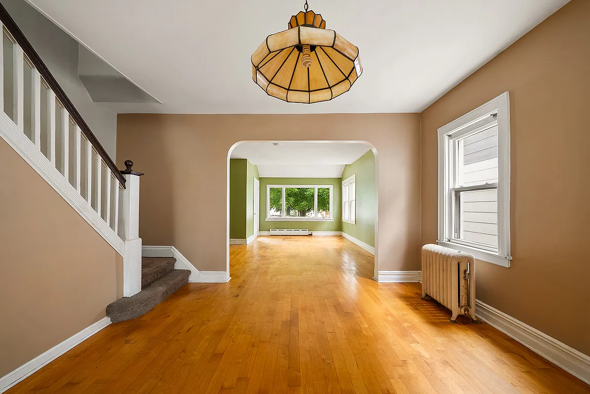 dining room and living room with wood floors, stair, and arched doorway