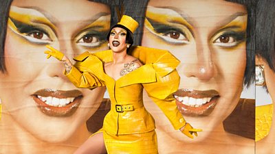 Drag Queen Anitea in a yellow leather dress suit and a yellow hat