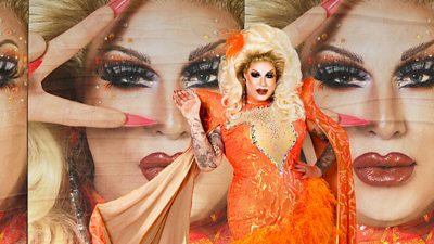 Drag Queen Kelly in an orange sequinned dress and a big blonde whig