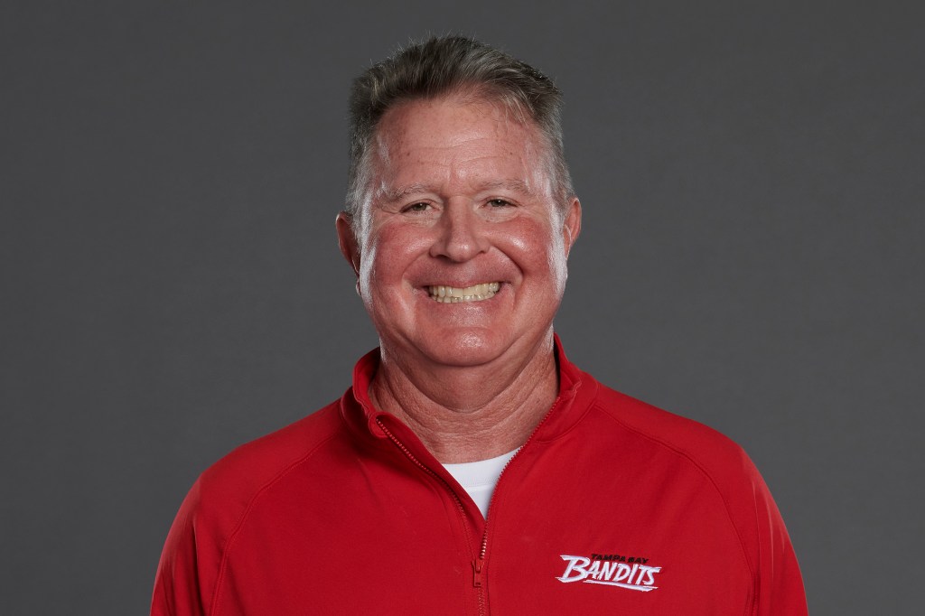 Headshot of a smiling man in a red jacket with a Tampa Bay Bandits logo.