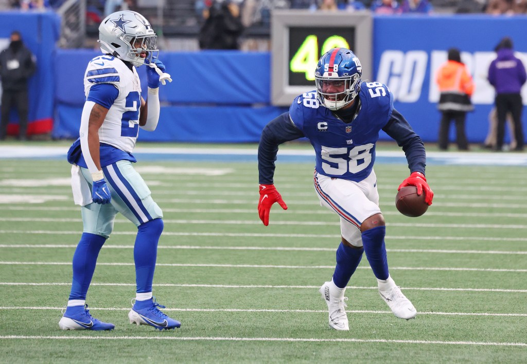 New York Giants linebacker Bobby Okereke (58) reacts after intercepting the ball while a Dallas Cowboys player looks on.