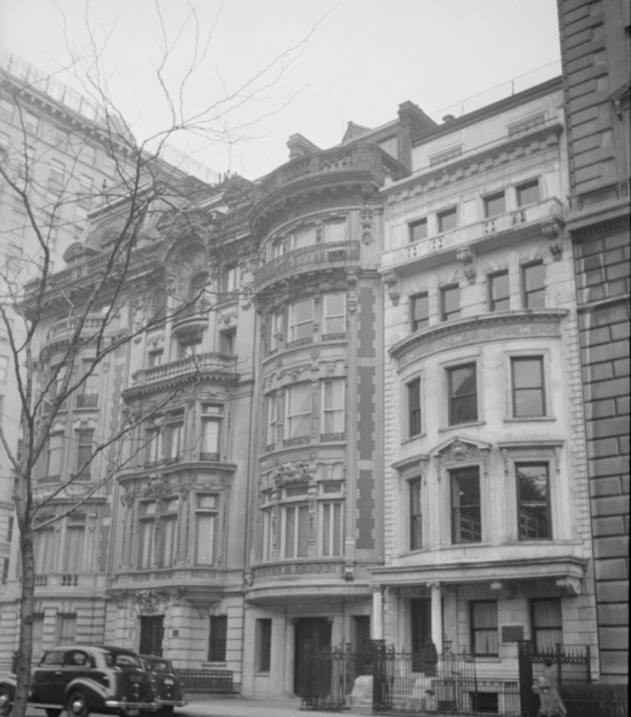 A historic building with ornate architectural features, including decorative balconies and large windows, captured in black and white.