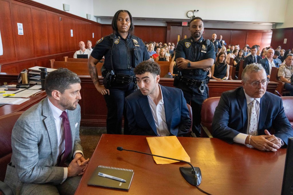Luigi Mangione, accused of killing UnitedHealthcare CEO Brian Thompson, appears in court with two police officers standing behind him.
