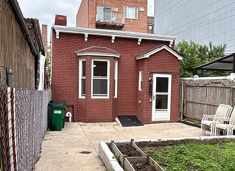 rear lot small house with a concrete patio and a raised area of soil