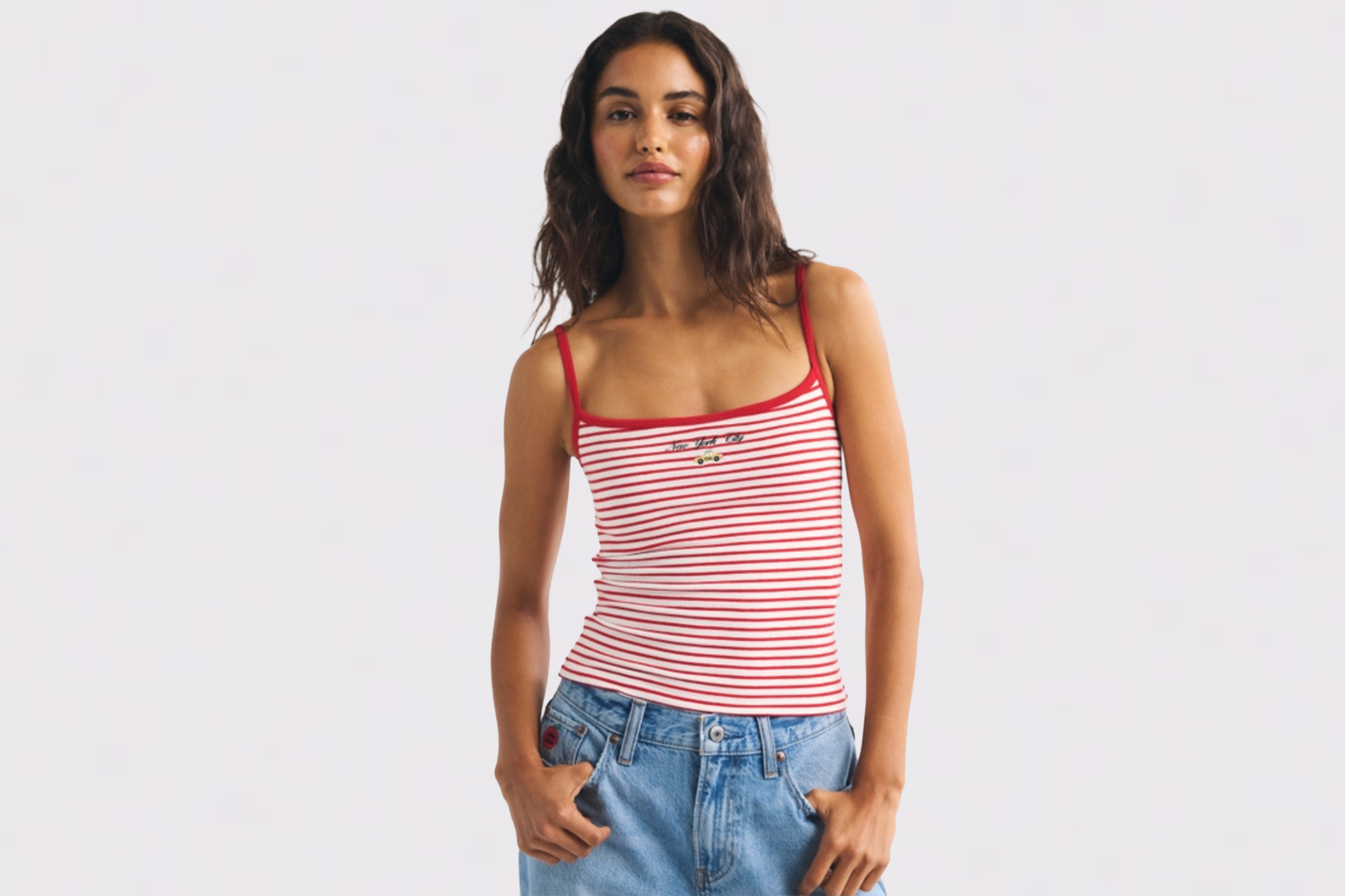 A woman modeling a red and white striped tank top with "New York City" embroidered on it.