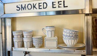 Russ &amp; Daughters x West Elm white ceramic serveware lined in blue pictured atop a mid-century style shelf framed in chrome