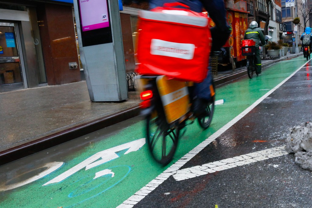 Delivery workers ride in a Chelsea, Manhattan bike lane,