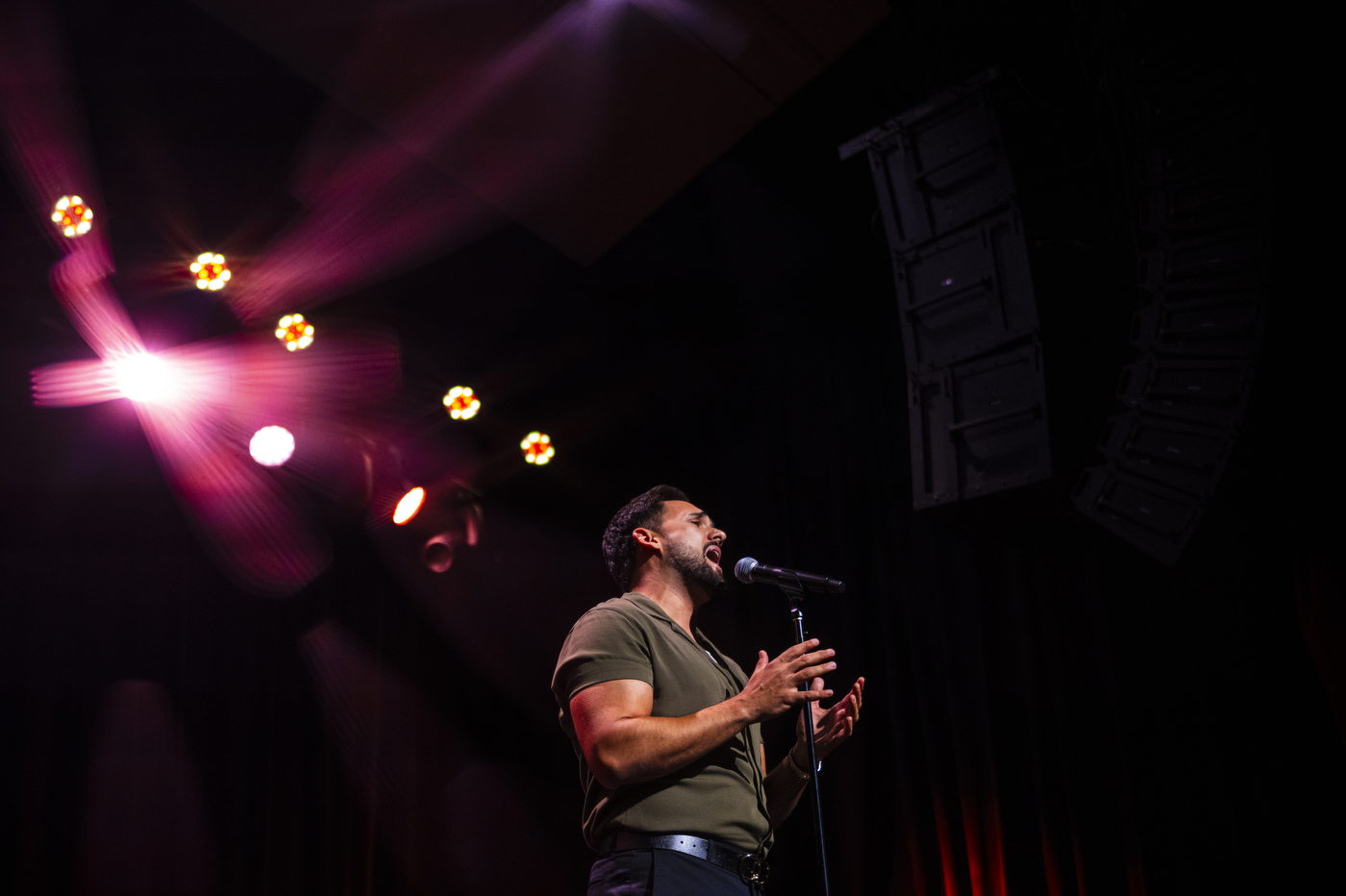A musician performs onstage under colorful lights during the New York City convocation.