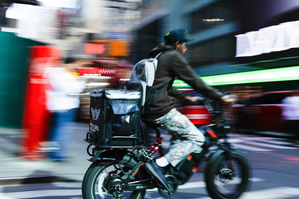 Delivery workers zip through Times Square on e-bikes,