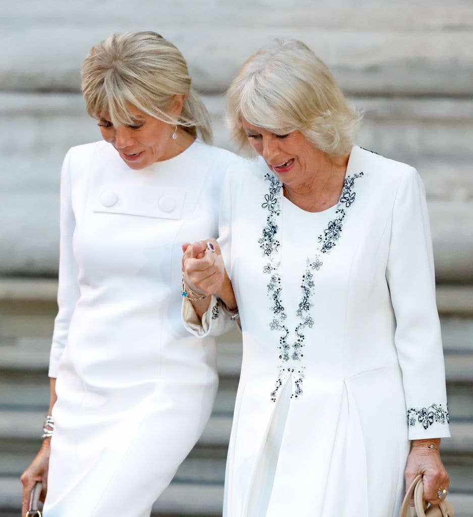 Brigitte Macron and Queen Camilla hold hands as they depart after attending a viewing of the Bayeux Tapestry Exhibition 