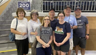 Fleming and Thoman stand in a stadium with five family members