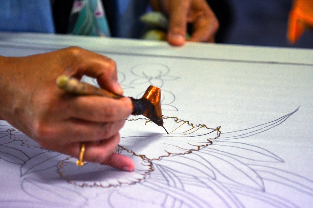 At her studio, Rosliza Muhammad carefully draws molten wax patterns with a canting. — Bernama pic