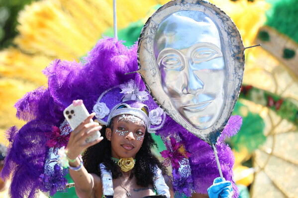 Participants take a selfie as they wait to walk in the West Indian Day Parade on Monday, Sept. 7, 2026, in the Brooklyn borough of New York. (AP Photo/Heather Khalifa)