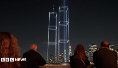 A group of people watching a drone light display showing the Twin Towers.