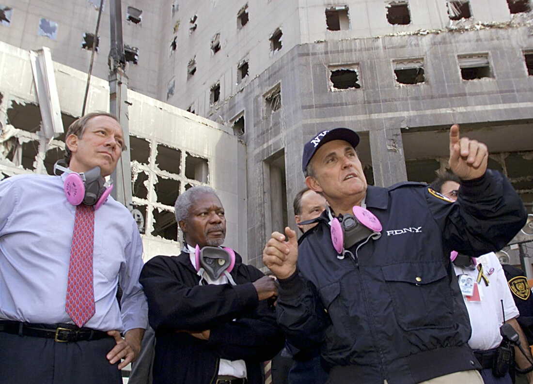 In this Sept. 18, 2001, photo, New York Governor George Pataki stands on the left side of the frame, with U.N. Secretary-General Kofi Annan in the center and New York City Mayor Rudy Giuliani on the right. They are at the World Trade Center attack site in New York City, and a heavily damaged building with missing windows rises in the background.