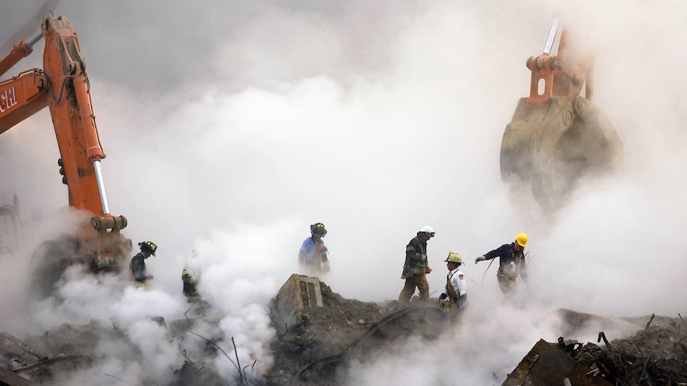 FILE - In this Oct. 11, 2001 file photo, firefighters make their way over the ruins of the...