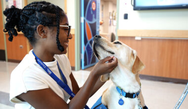 An Elmhurst Hospital volunteer interacts with Weasley outside of the Employee Wellness Center.