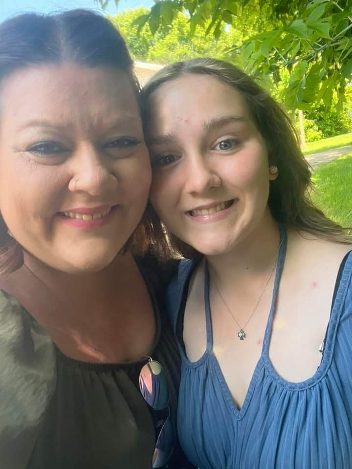 Two women look at the camera, smiling.