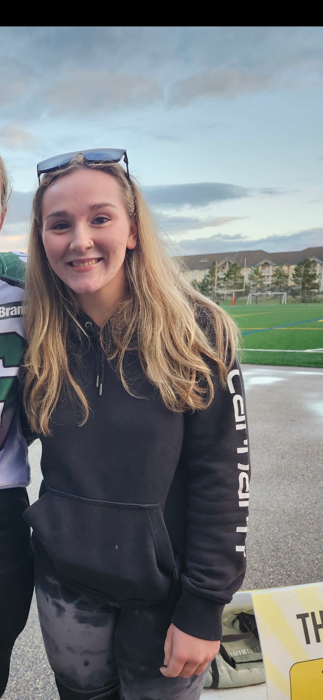 A teenage girl in a black sweater smiles at the camera.