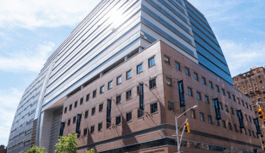 Street view image of Baruch College's 14-story Newman Vertical Campus building that features a tiered glass-enclosed atrium.