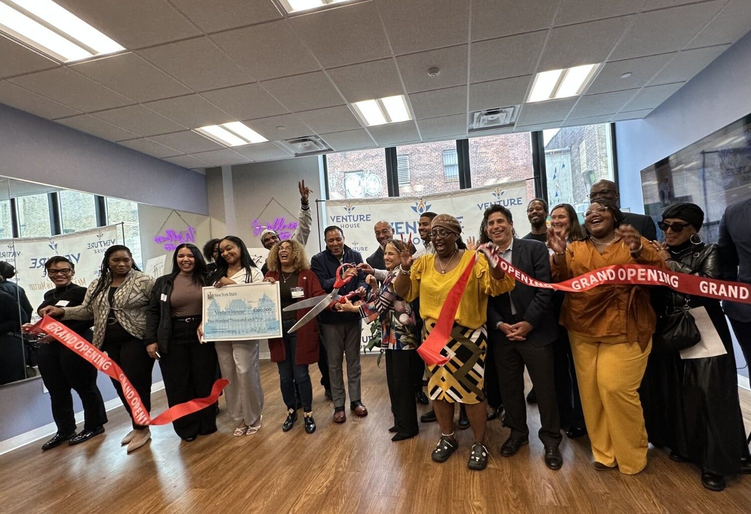 Diverse group of adults celebrates ribbon cutting at Venture House in the Bronx.