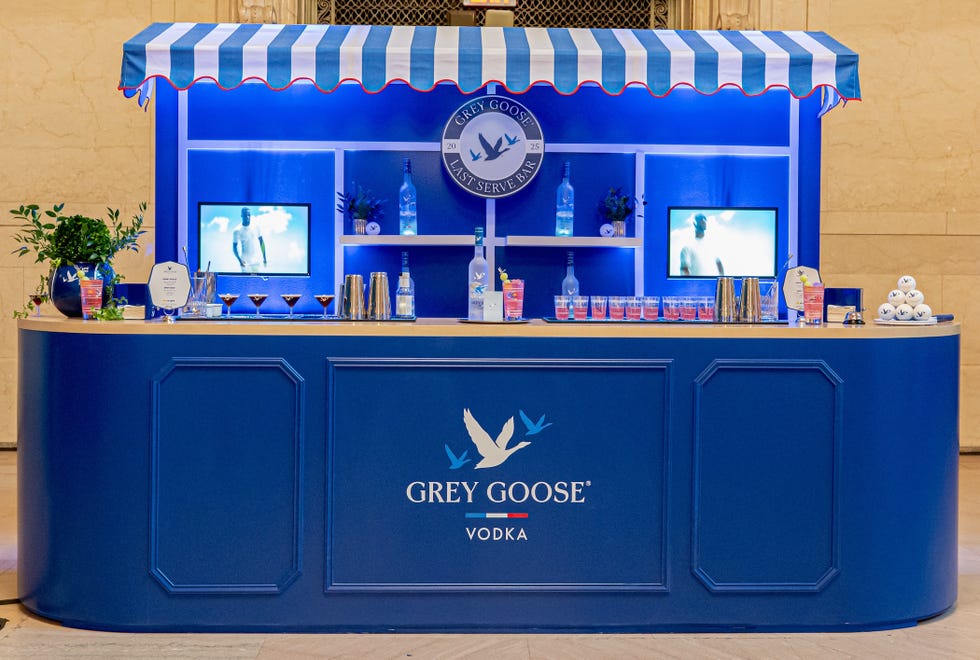 Blue bar display for Grey Goose vodka with various drinks, screens, and decorative elements.