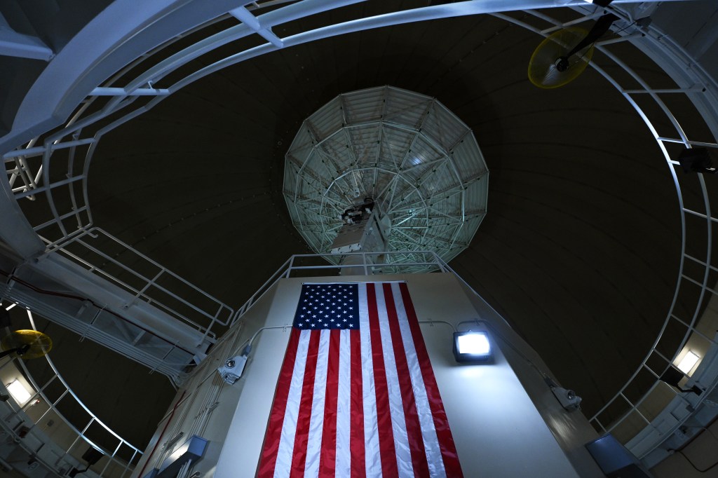 An antenna with the American flag hanging below is seen at Ka'ena Point Space Force Station.