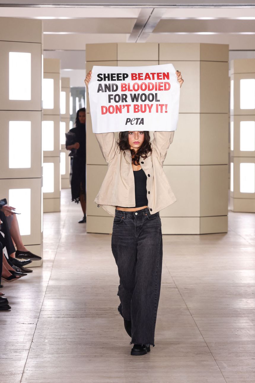 A protester holds a sign on the COS runway.