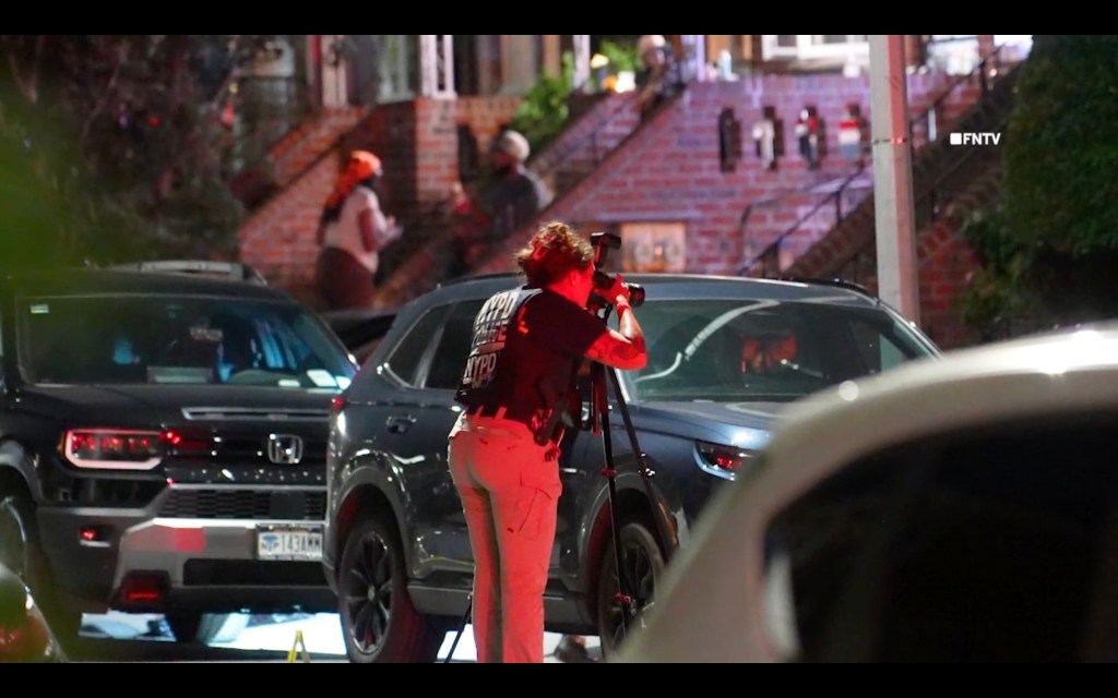 A NYPD Crime Scene Unit member photographs the scene of a shooting in Brooklyn, NY.