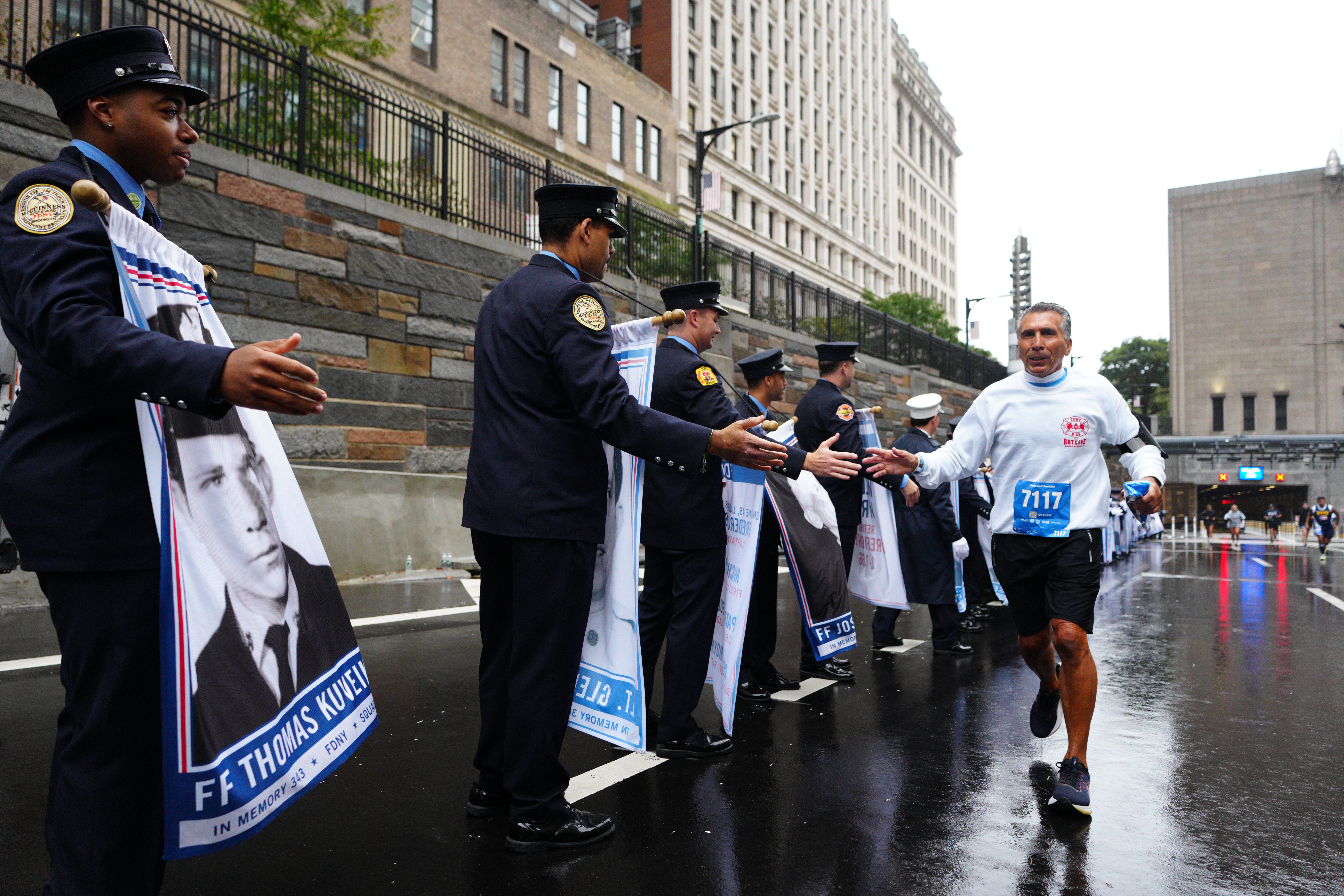 A runner shakes hands with a first responder holding a memorial banner during the Tunnel to Towers NYC 5K Run & Walk.
