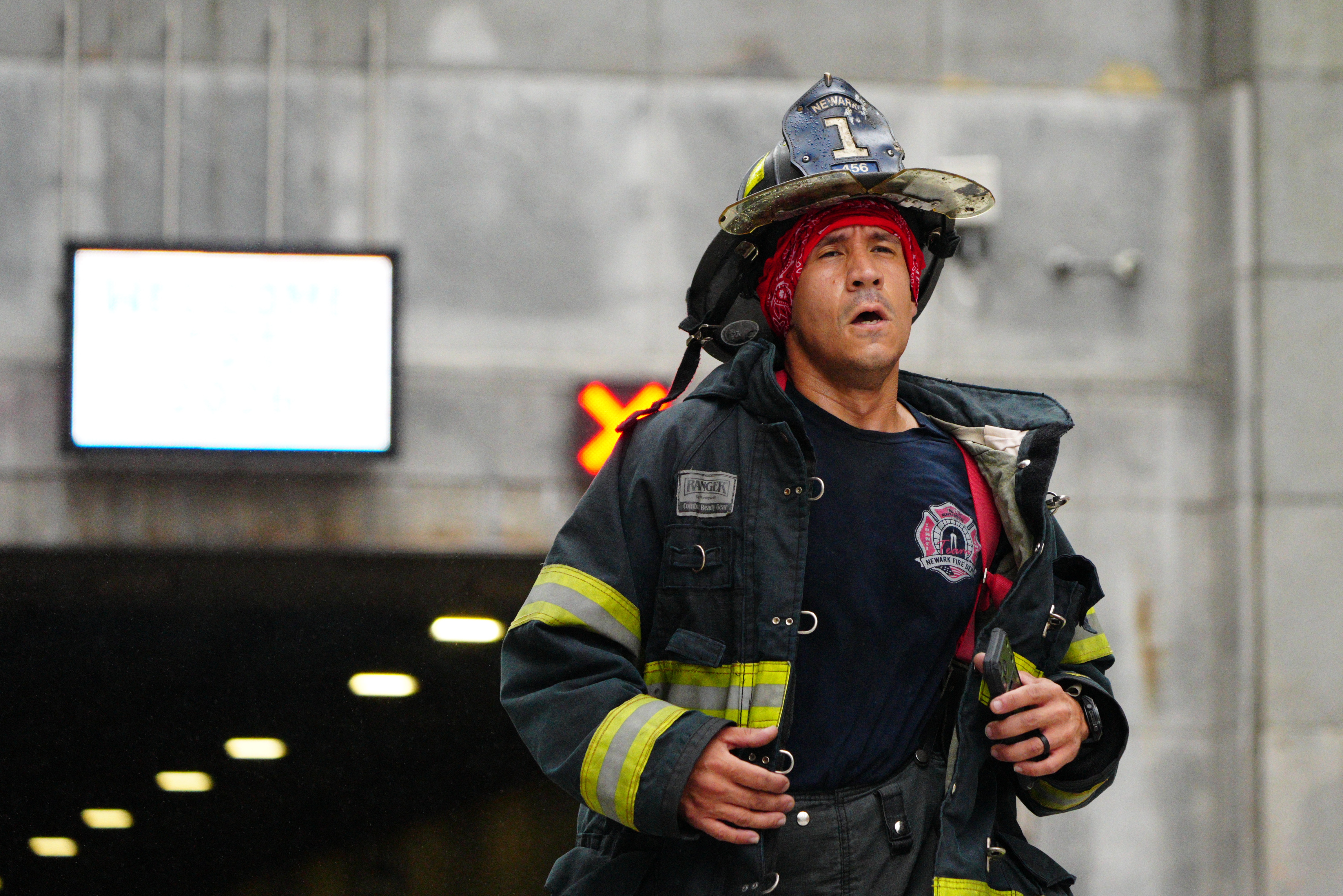 A firefighter in uniform with a red bandana and helmet runs past a tunnel entrance.