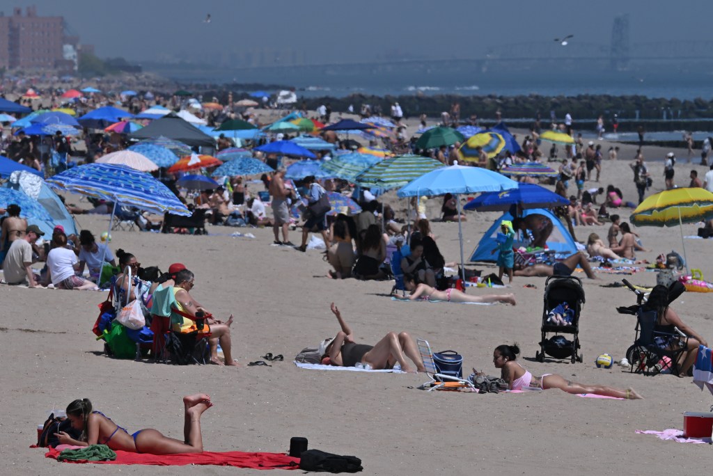 View of Coney Island Beach with many people under colorful umbrellas.