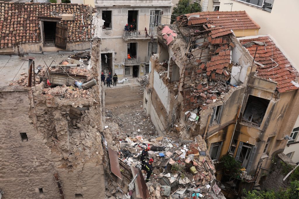 Firefighters and special disaster response unit members search through the rubble of a collapsed building.