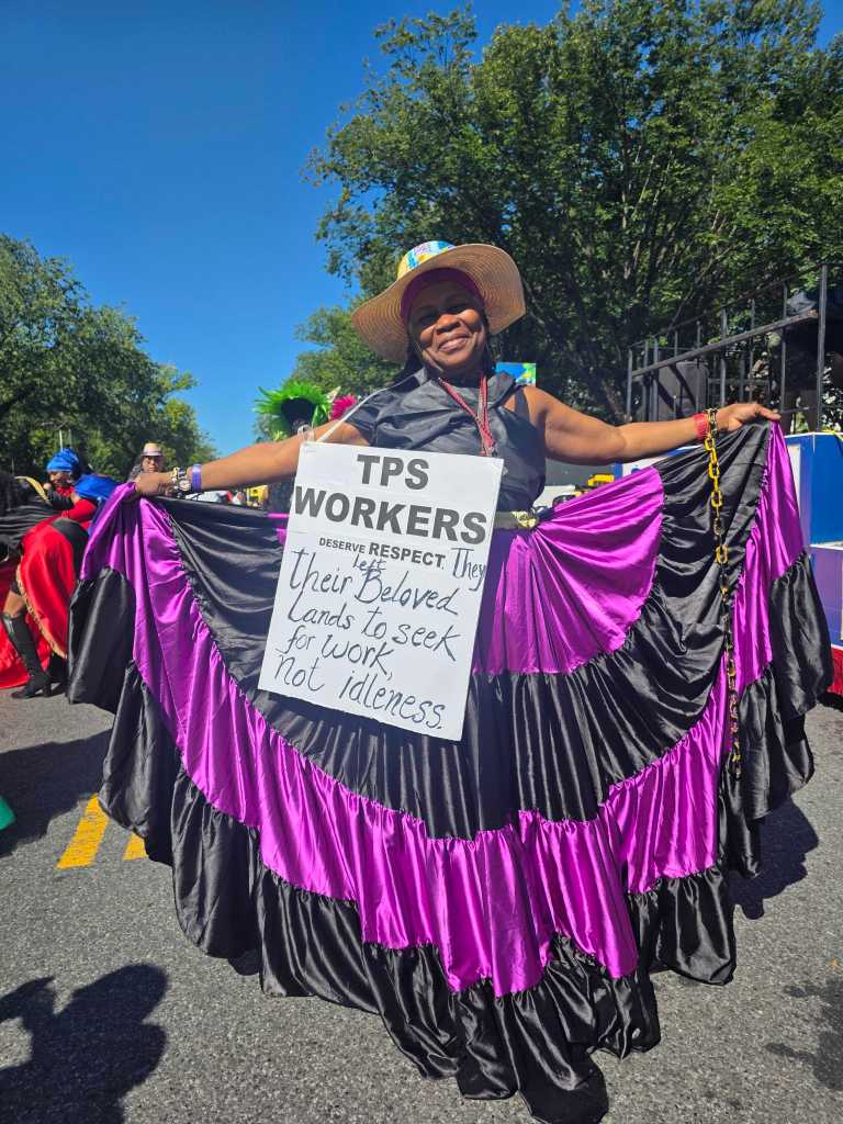 Jocelyne Gay marches with a sign carrying a message in support of the TPS bill, S. 4814, during the West Indian Day Parade in Brooklyn, N.Y., Sept. 7, 2026. Some elected officials are urging Congress to pass the measure. Photo by Darlie Gervais for The Haitian Times.