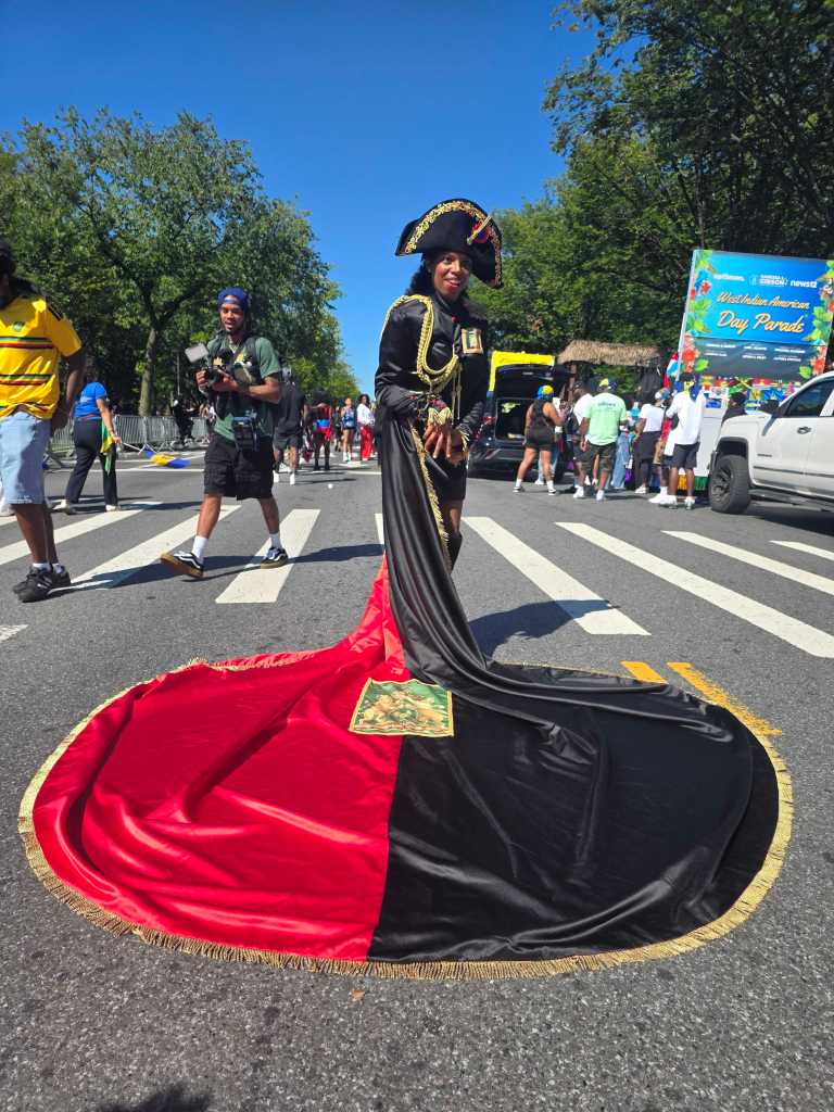 A masquerader honoring revolutionary heroine Sanité Bélair dons the historic red and black attire, echoing the colors of Haiti’s original republic flag. Photo by Darlie Gervais for The Haitian Times.
