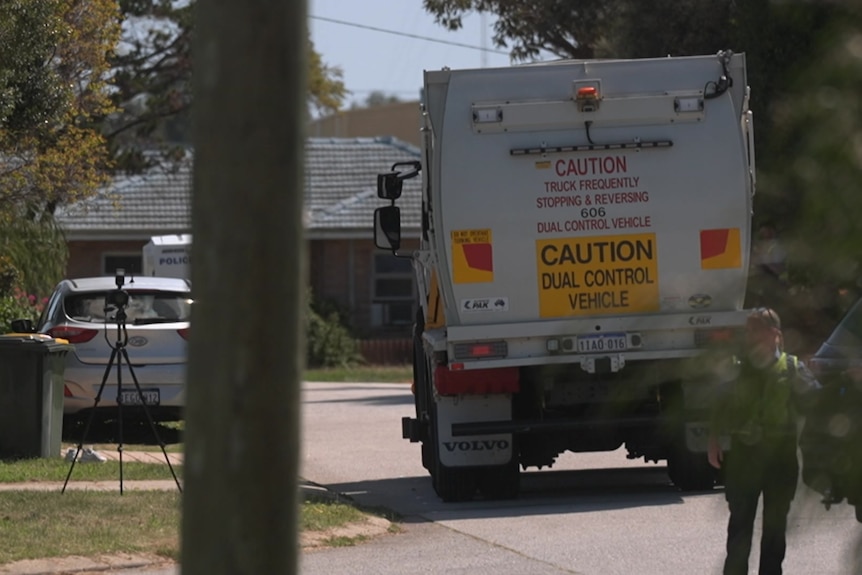 A suburban street with a garbage truck on it.