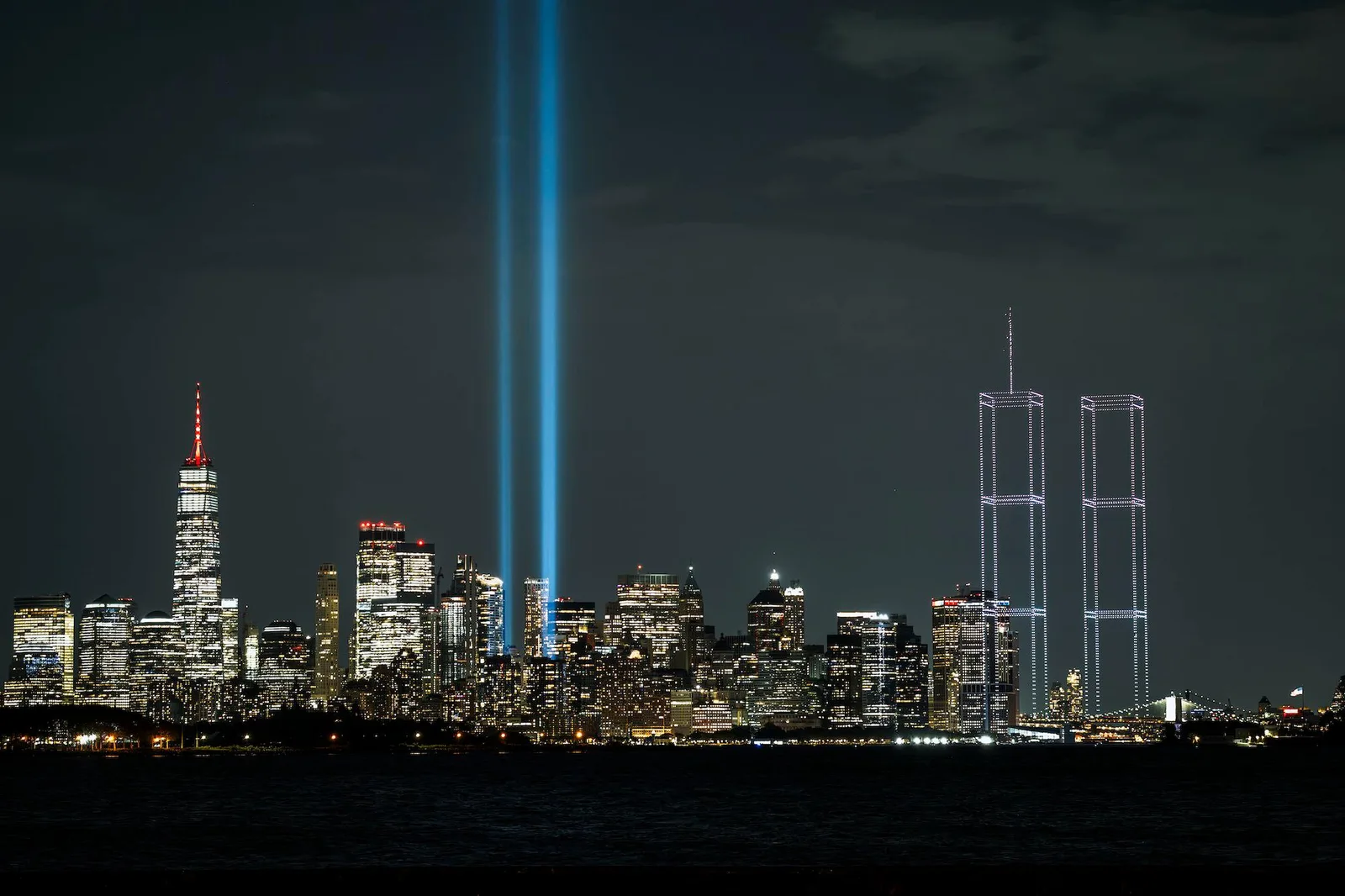 Two blue Tribute in Light beams and a light-outlined recreation of the Twin Towers rise above the Manhattan skyline at night