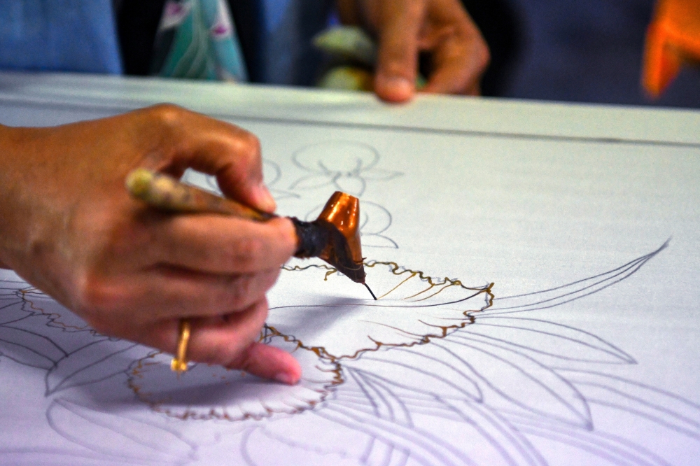 At her studio, Rosliza Muhammad carefully draws molten wax patterns with a canting. — Bernama pic