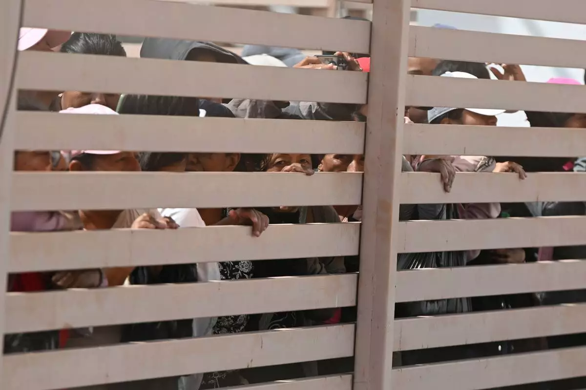 Relatives of crew members of the boat Maria Candelaria peer through a fence outside a police facility in Manta, Ecuador, Monday, Sept. 7, 2026, as they wait for the crew to return after the boat was intercepted by U.S. authorities on suspicion of alleged drug trafficking. (AP Photo/Ariel Ochoa)
