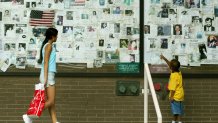 Crystal (L) and Jordan Tirado view September 11th missing person posters August 22, 2002, in New York City. The posters were still attached to a wall outside Saint Vincent's Hospital.